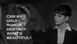 Still shot of a film trailer showing Shirley MacLaine looking down at the left and Audrey Hepburn to her right staring at her, in a bedroom. The words "Can an ugly rumor destroy what's beautiful?" obscure much of MacLaine's face